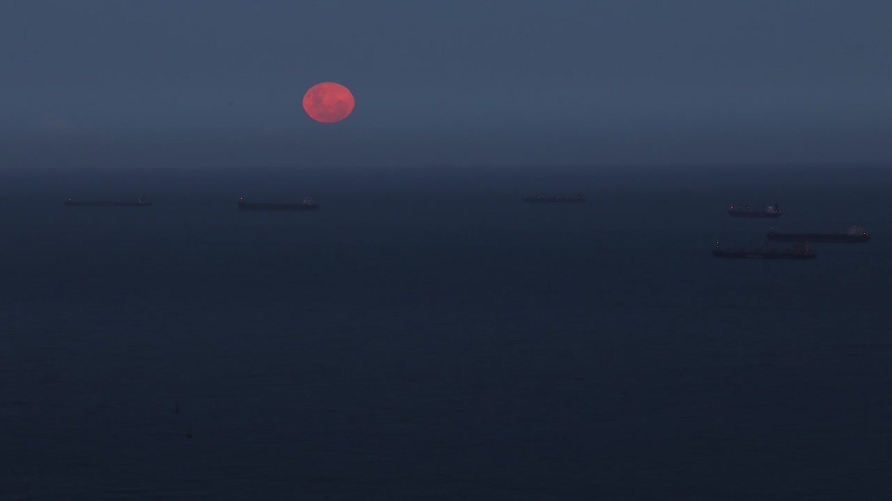 full moon raising from the sea between some ships.Shot with canon 7d mark ii