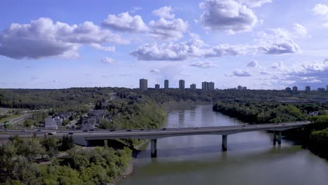 aerial hold over james macdonald bridge on a hot summer day at the north saskatchewan river right by downtown edmonton alberta canada road leading to the downtown city core inbetween a lush green park