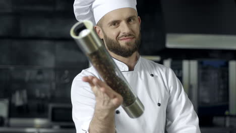 retrato de chef masculino en un restaurante de cocina. chef masculino jugando con la caja de pimienta