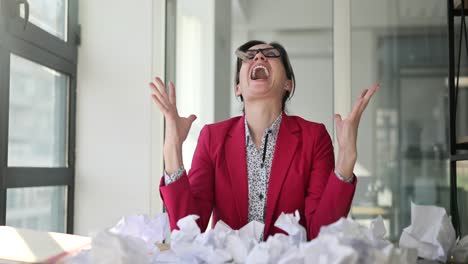 businesswoman overwhelmed and frustrated by work with crumpled paper