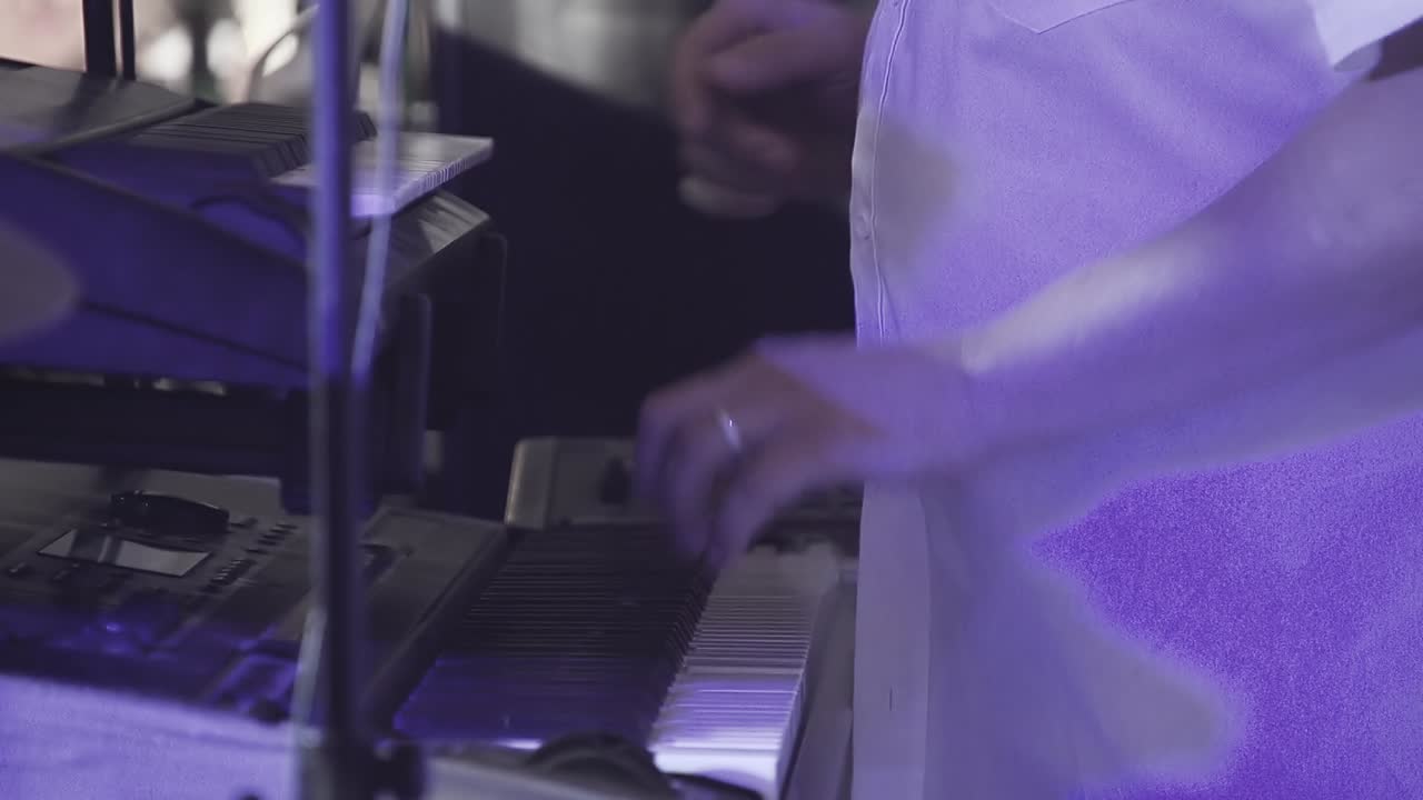 el tecladista toca varios instrumentos musicales en un concierto como parte de un grupo musical