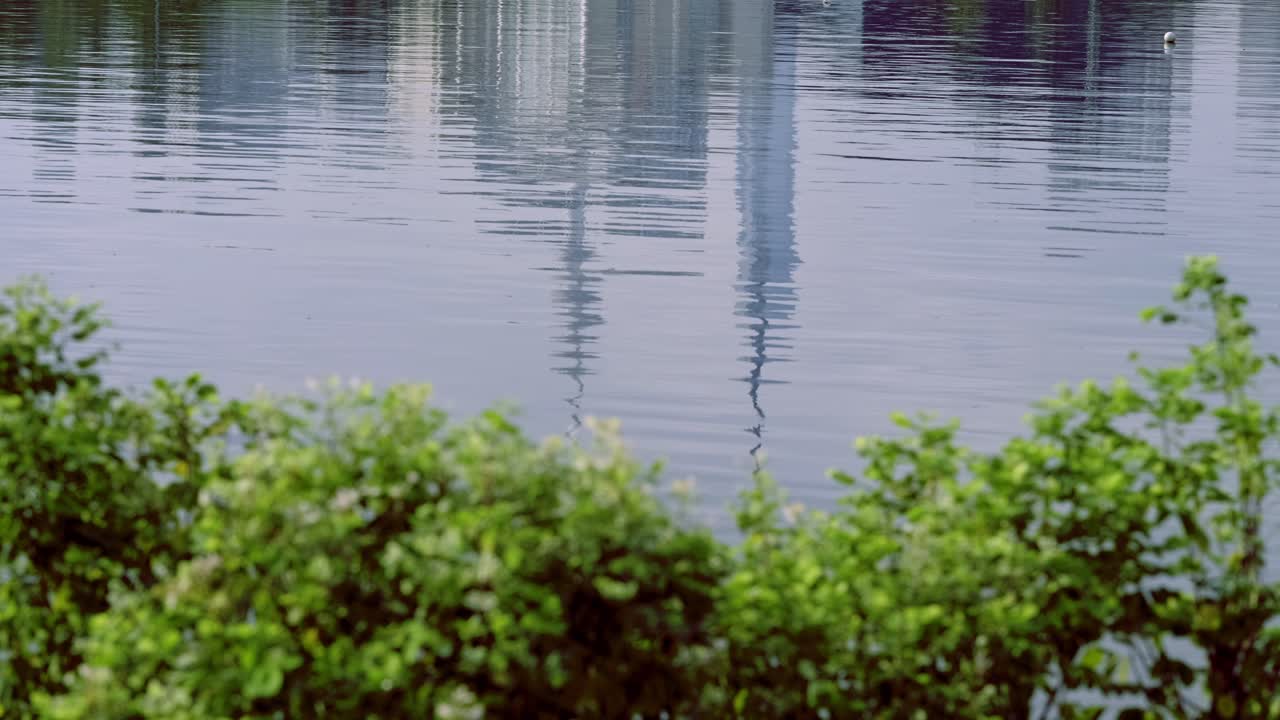 Abstract reflection of modern city skyscrapers shimmering on the surface of the Titiwangsa Park lake water