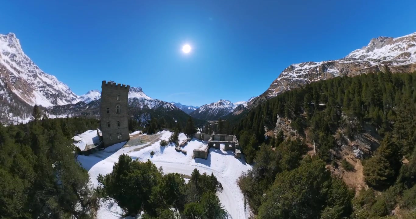 Drone view over green pine forest valley and snow-capped peaks at Maloja Pass in Switzerland. Aerial forward