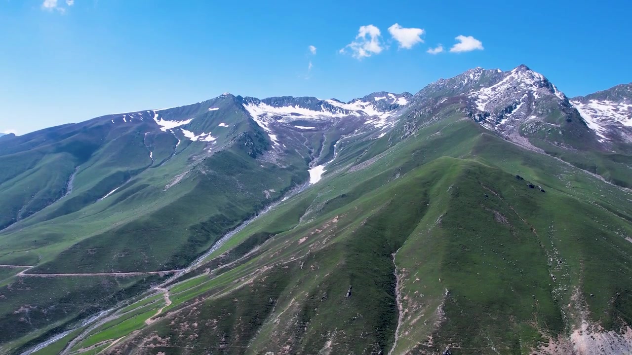 Crinali verdi conducono alle cime innevate dell'Hindu Kush al Passo Badgoi, Kalam, Pakistan.