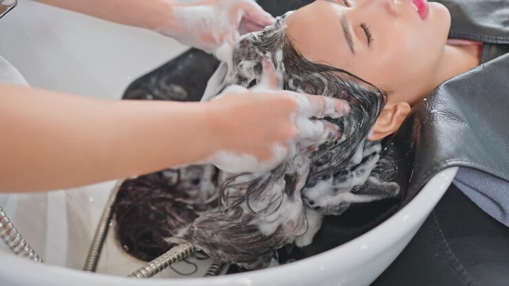 uma mulher a lavar o cabelo num salão de beleza.