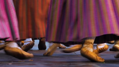 adult dancers in traditional folk costumes perform in a dance performance in open air, sunny evening, latvian national culture, medium shot of feet in simple footwear made of one piece of leather