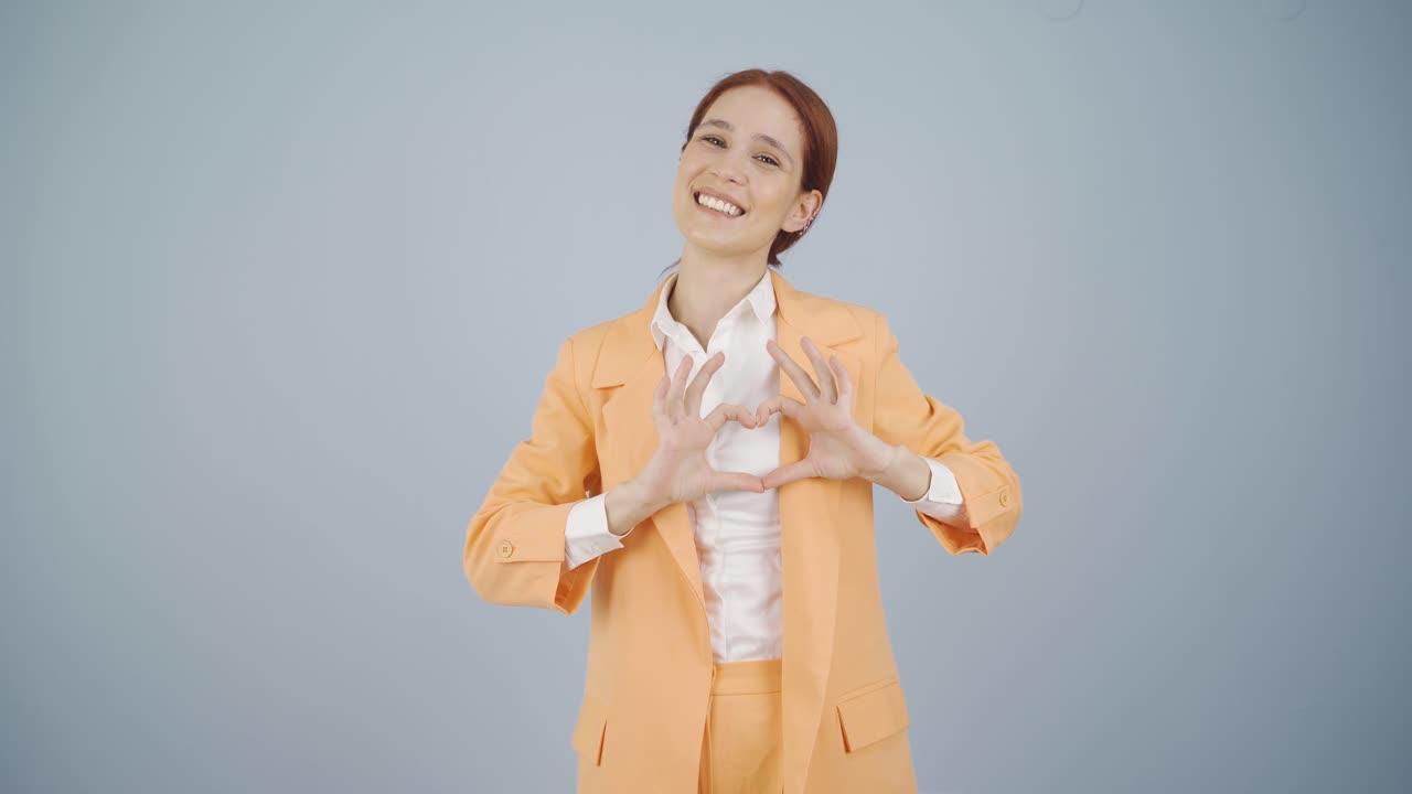 비즈니스 여자가 카메라에 심장을 만들고 있습니다.