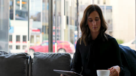 Front-view-of-beautiful-caucasian-businesswoman-using-mobile-phone-while-having-coffee-in-hotel-4k