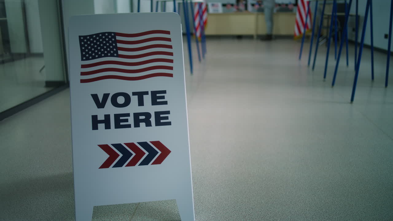 African American Male Voter Takes Paper Ballot at Polling Station African American Male Voter Walks for Registration Table at Polling Station Takes Paper Ballot Voting Booths with us Flag Logo and Sign Calling to Vote Election Day in the United States of America