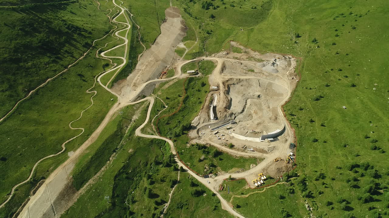 Top down aerial drone shot of a dam construction site in the alpine mountains
