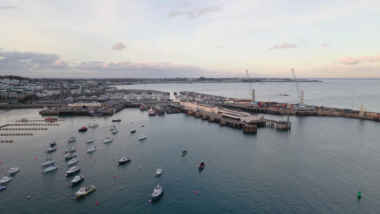 Porto di St Peter Port, Guernsey, drone che scende volando verso nord sopra il porto al tramonto, mostrando barche all'ormeggio, banchine dei traghetti, Cambridge Berth e vedute verso St Sampson.