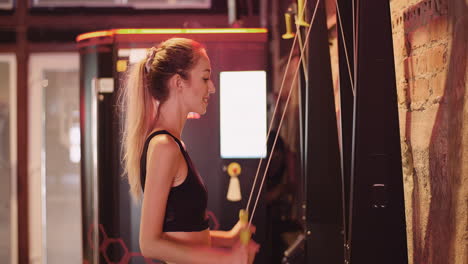 Side-View-Of-Confident-Young-Woman-Exercising-On-Cable-Machine-During-Fitness-Training