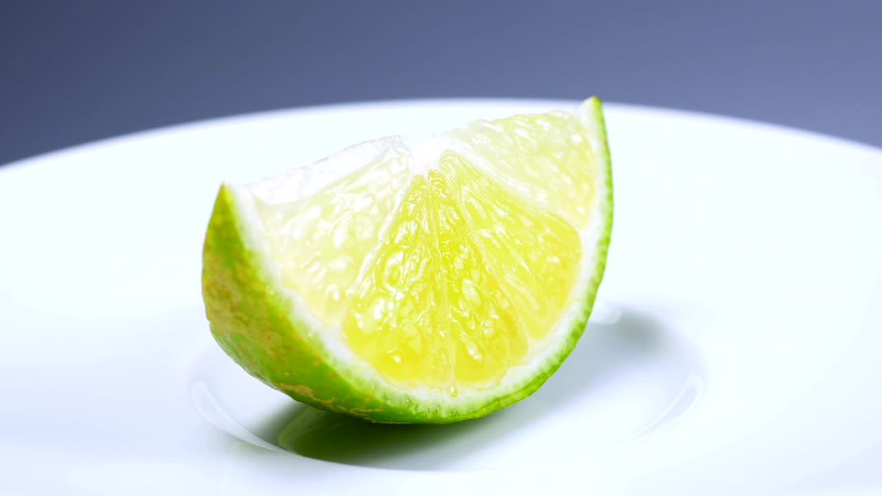una rebanada de limón verde está girando lentamente en el estudio con los detalles.
