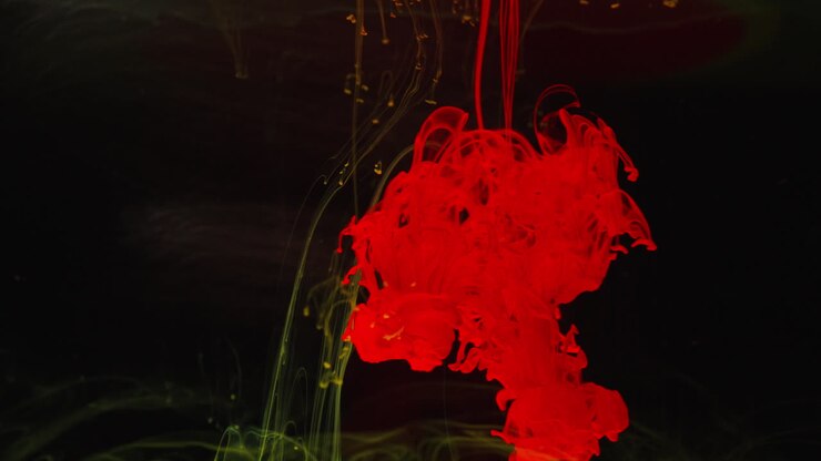 In un'affascinante macrofotografia, inchiostro rosso e verde si mescolano nell'acqua