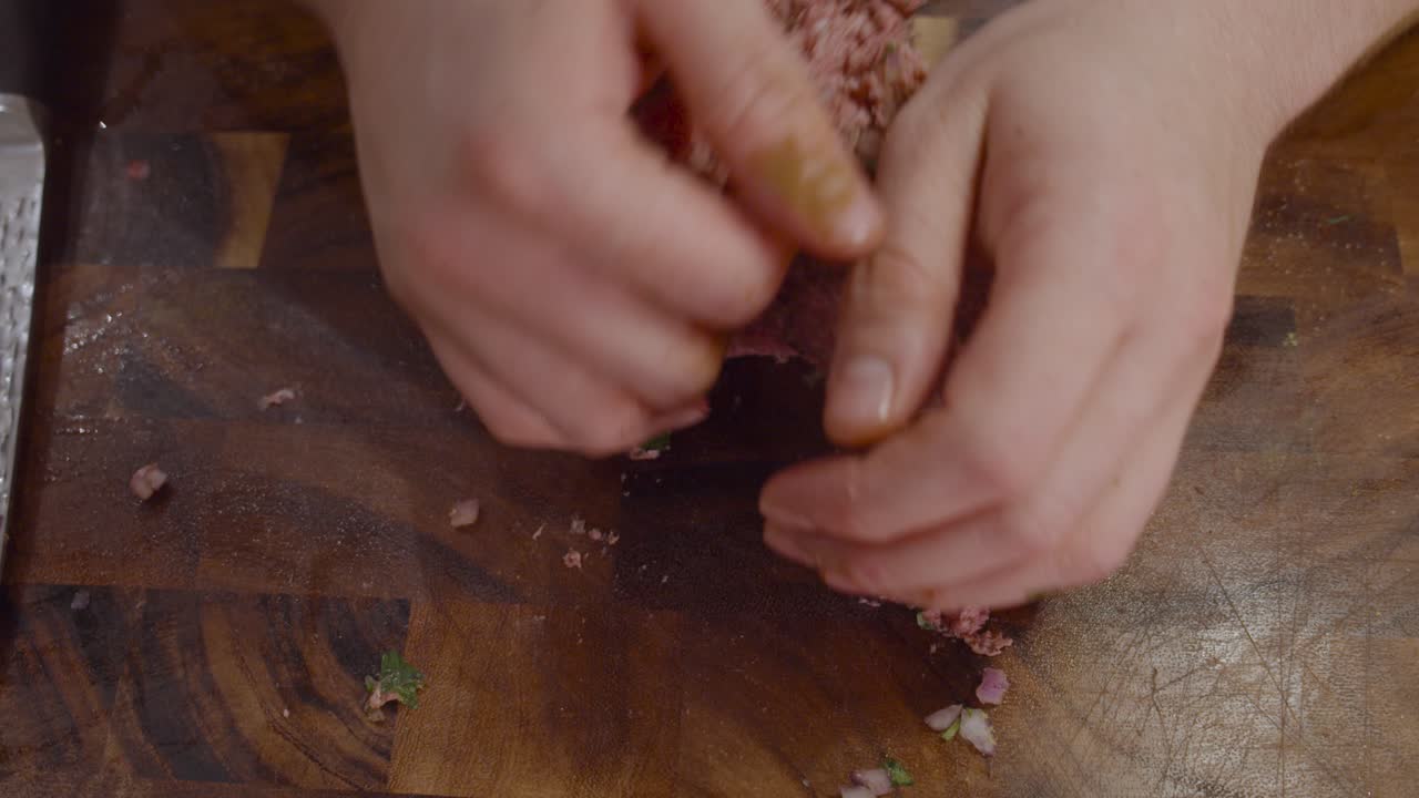 крупный план рук, разминающих мясо на деревянной разделочной доске для приготовления фрикаделек