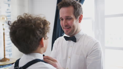 padre e hijo con trajes a juego preparándose para la boda en casa