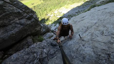 a strong and fit man is climbing up alone in the mountains of switzerland while holding his selfie stick