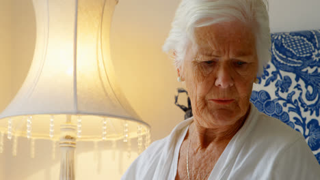 Front-view-of-senior-Caucasian-woman-having-medicine-with-glass-of-water-on-bed-in-bedroom-4k