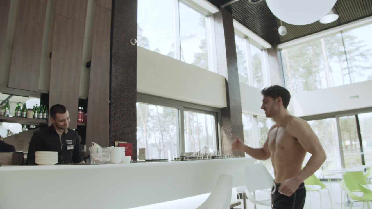 спортивный мужчина приходит в кафе спа. красивый парень приветствует бармена в оздоровительном курорте
