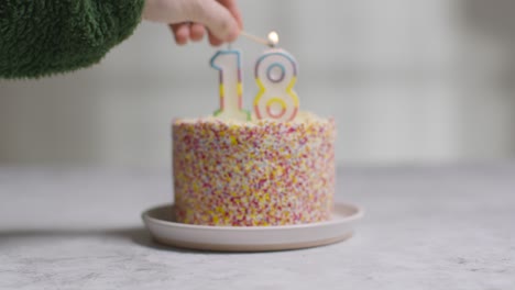 bolo de aniversário de foto de estúdio coberto com enfeites e vela comemorando décimo oitavo aniversário sendo aceso