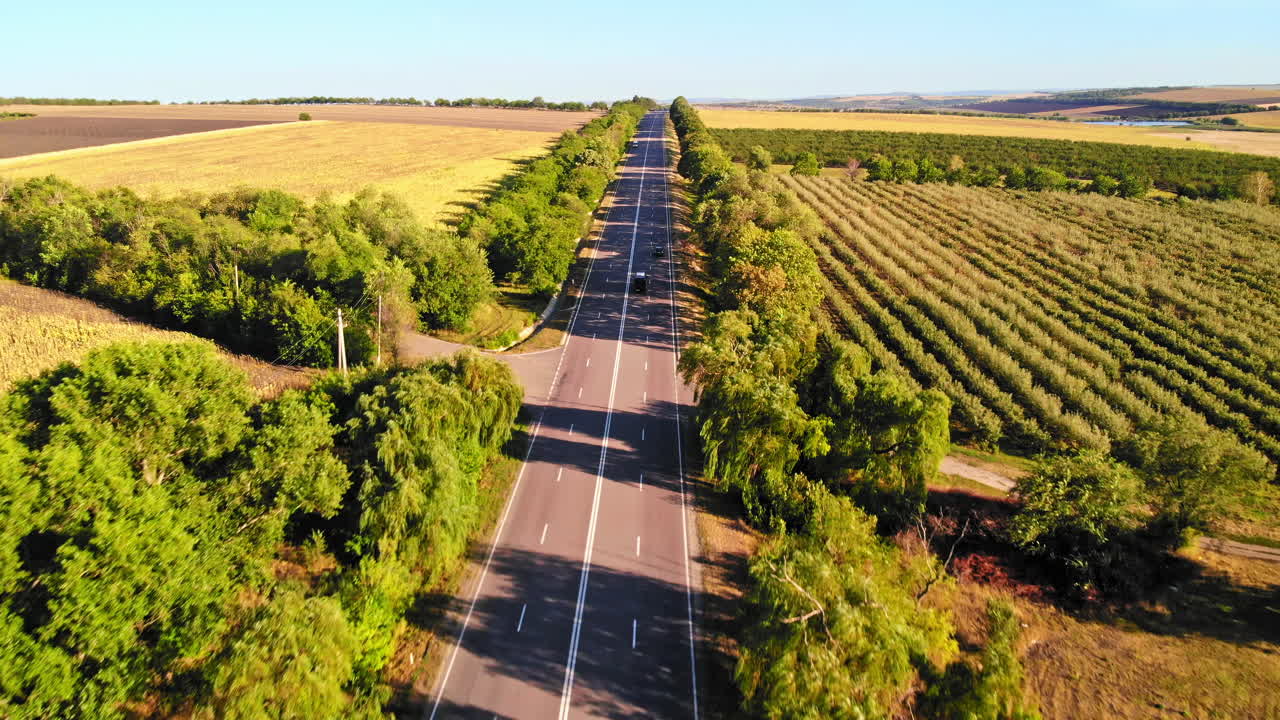 Aerial drone view of a road with moving car in highland. Green fields and hills from north part of Moldova