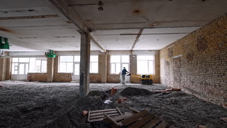 man using a machine to make floors inside the large premises. interior works at the construction.