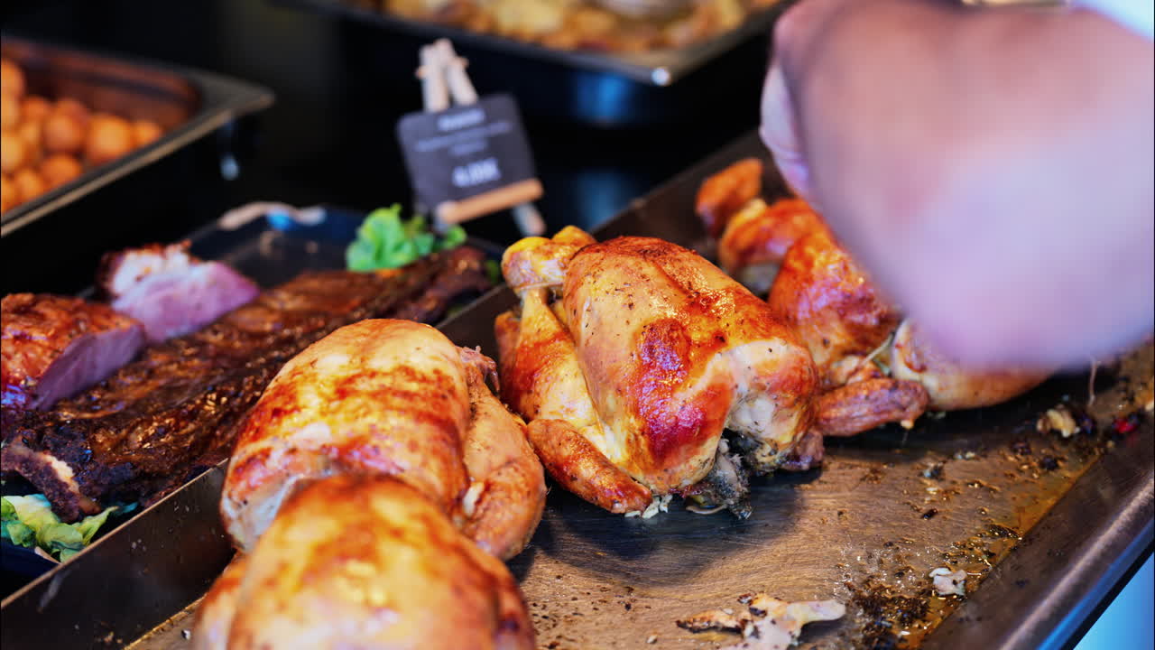 Close up of a man cutting up grilled chickens at a food stand