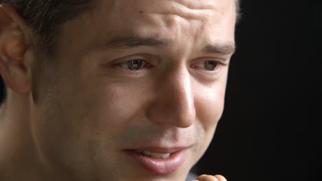 studio shot of tearful man against black background