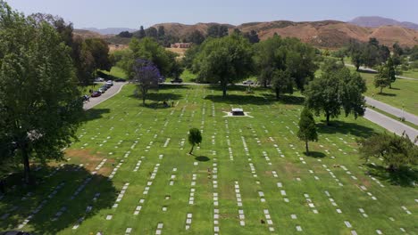 Aerial-shot-flying-over-the-United-States-flag-and-tilting-down-to-rows-of-headstones-at-a-mortuary-in-California