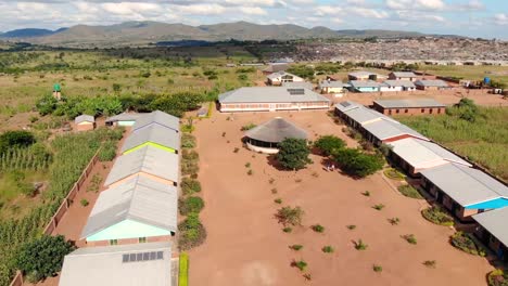 Couple-of-Refugees-Walking-in,-Central-Square-of-Dzaleka-Refugee-Camp,-Aerial-View