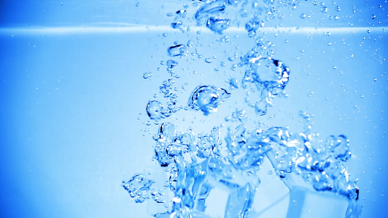 얼음 큐브가 공기 거품으로 물에 떨어집니다.