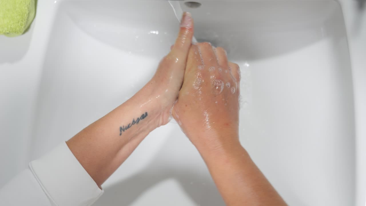 Point of view of washing hands in a bright clean bathroom sink