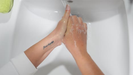 Point-of-view-of-washing-hands-in-a-bright-clean-bathroom-sink