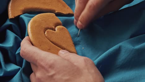 men's hands break sugar cookies candy in the shape of a heart.