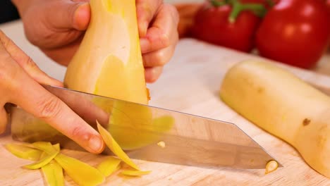 hands peeling squash with knife on cutting board