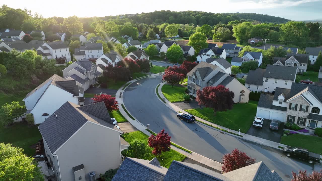 Modern and noble residential Area in springtime. Sunset time with colored trees and one family homes in suburbia of PA, USA. Aerial approaching wide shot. Noble suburb housing area in United States.