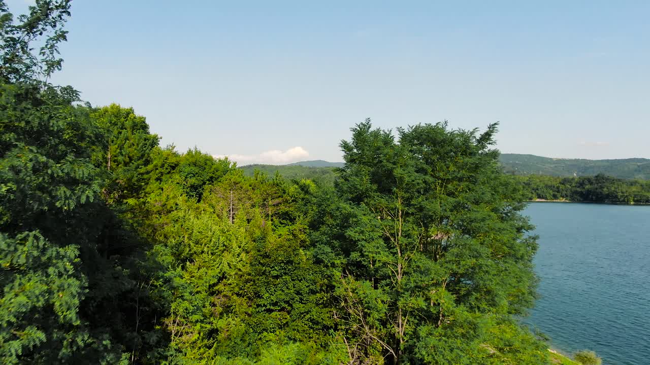 유럽의 부토니가 호수의 나무와 해안선 위로 4k 공중 드론이 발사되었습니다.