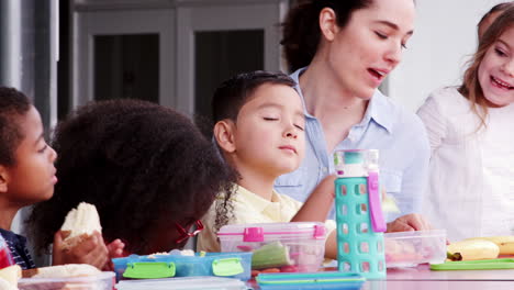 Elementary-school-kids-and-teacher-at-a-table-at-lunch-break