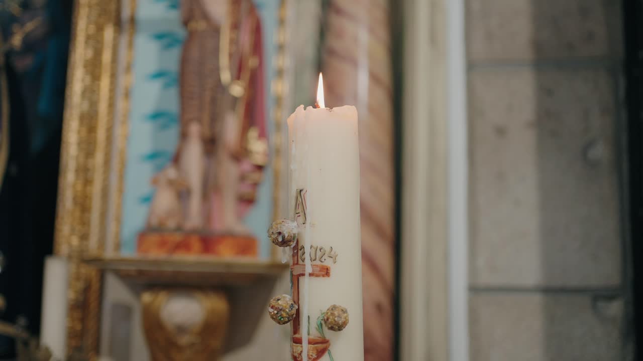 Warm baptismal candle glowing with ornate sacred charm