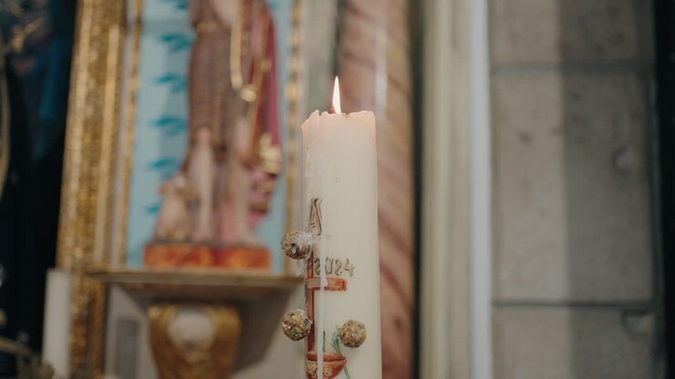 Warm baptismal candle glowing with ornate sacred charm