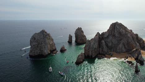 Vista-Aérea-Alrededor-De-Los-Barcos-Que-Conducen-Alrededor-Del-Arco-Rocoso-De-Cabo-San-Lucas,-México---Dando-Vueltas,-Tiro-De-Drones