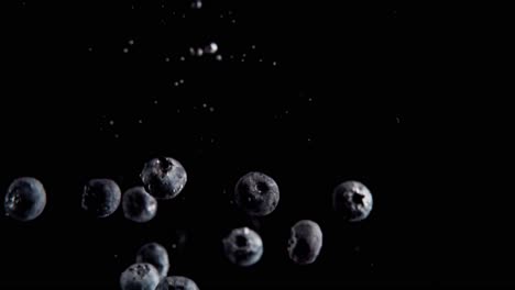 currants falling into water super slowmotion, black background, lots of air bubbles, 4k240fps