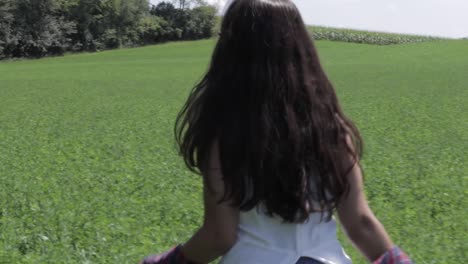 slow tracking shot of a young woman sauntering through a lucious greem field