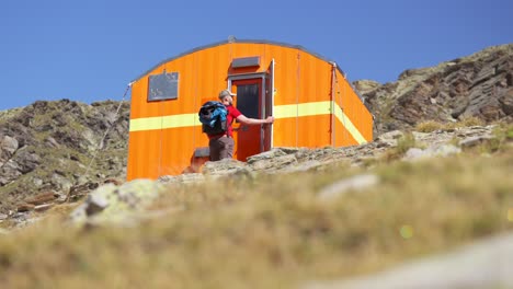 tomada de ángulo bajo de un excursionista masculino abriendo la puerta de un bivaco anghileri-rusconi