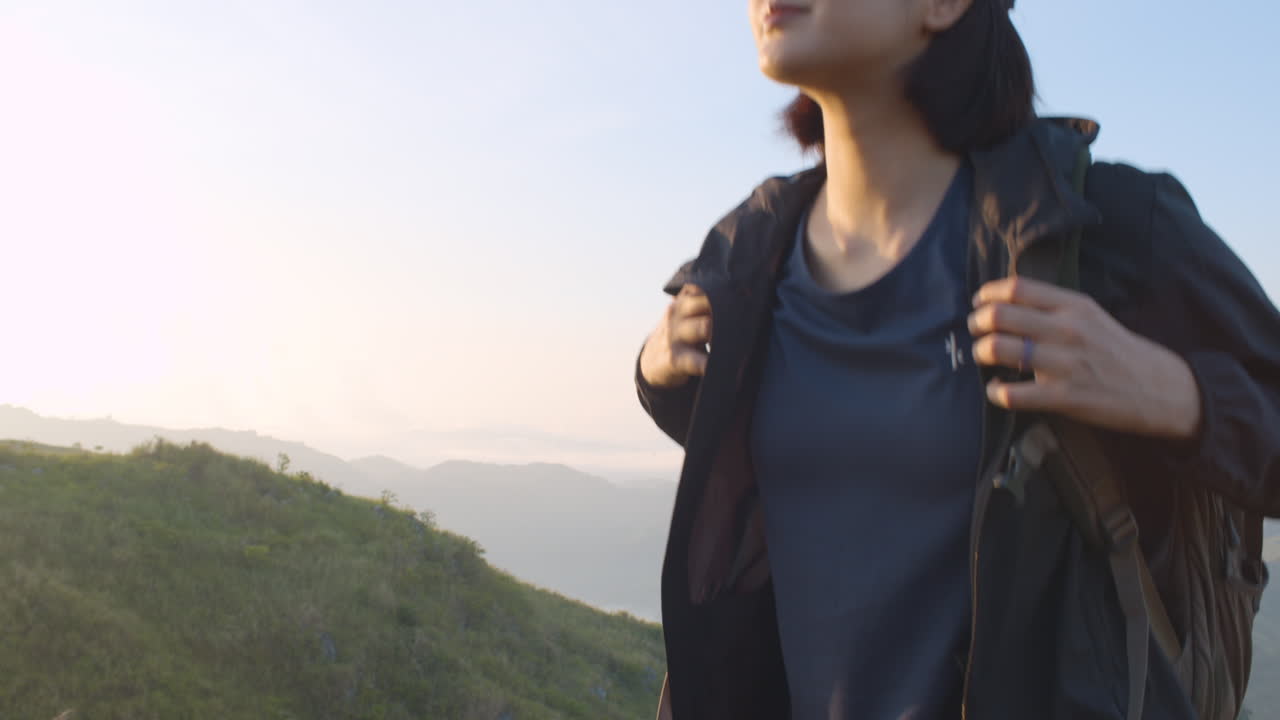 산을 오르는 동안 배낭을 들고 단호한 젊은 여성의 슬로우 모션 중간 샷