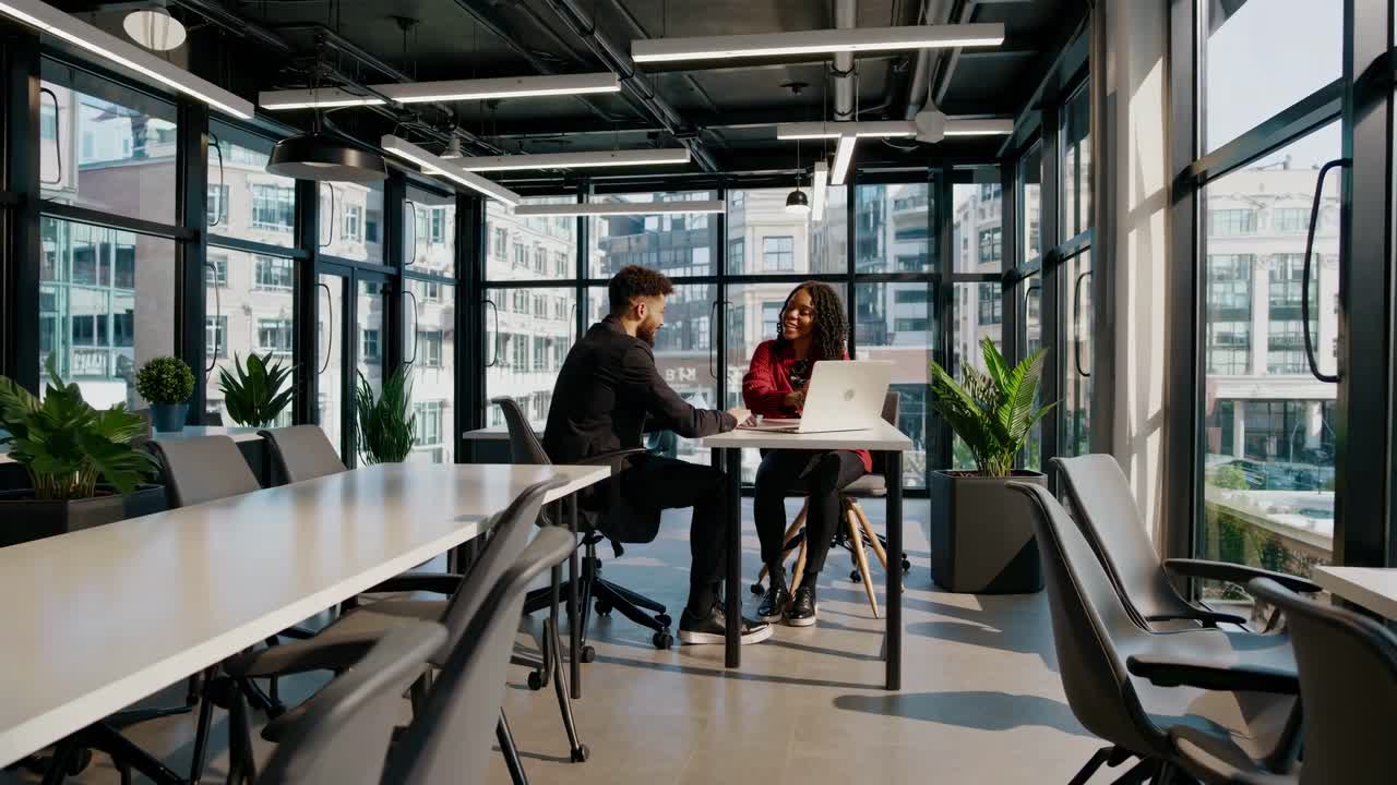 Wide-angle shot of a modern office with two people discussing work