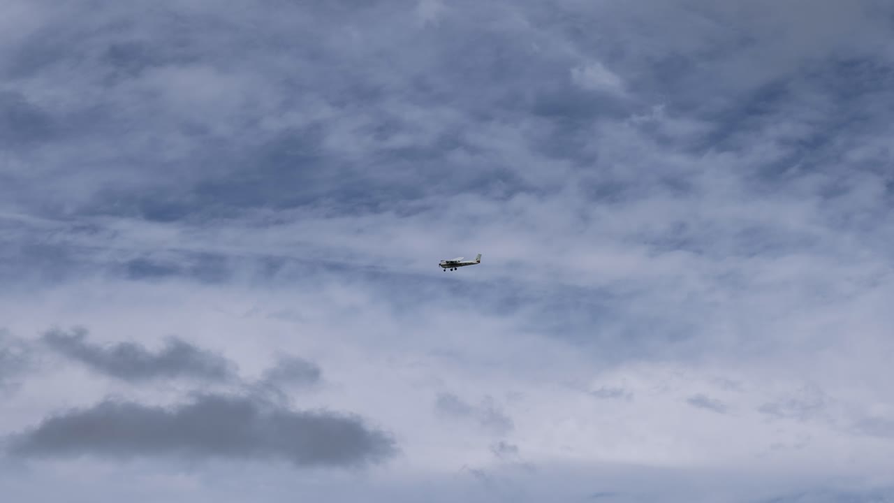 An airplane moves across a cloudy sky
