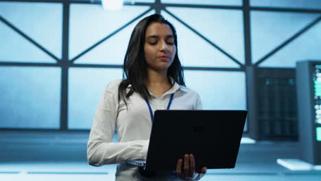 tracking shot of woman in server hub ensuring networks are secure