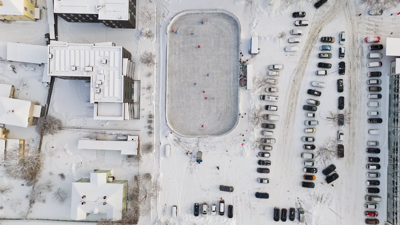 Top down drone shot over a game at a urban ice hockey rink, sunny, winter day