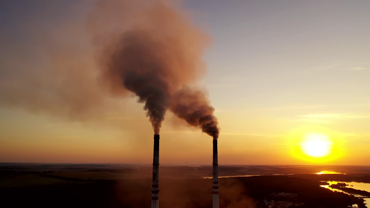 Pollution of the environment. Toxic smoke goes from industrial pipes of the factory at a beautiful sunset. Ecological disaster.